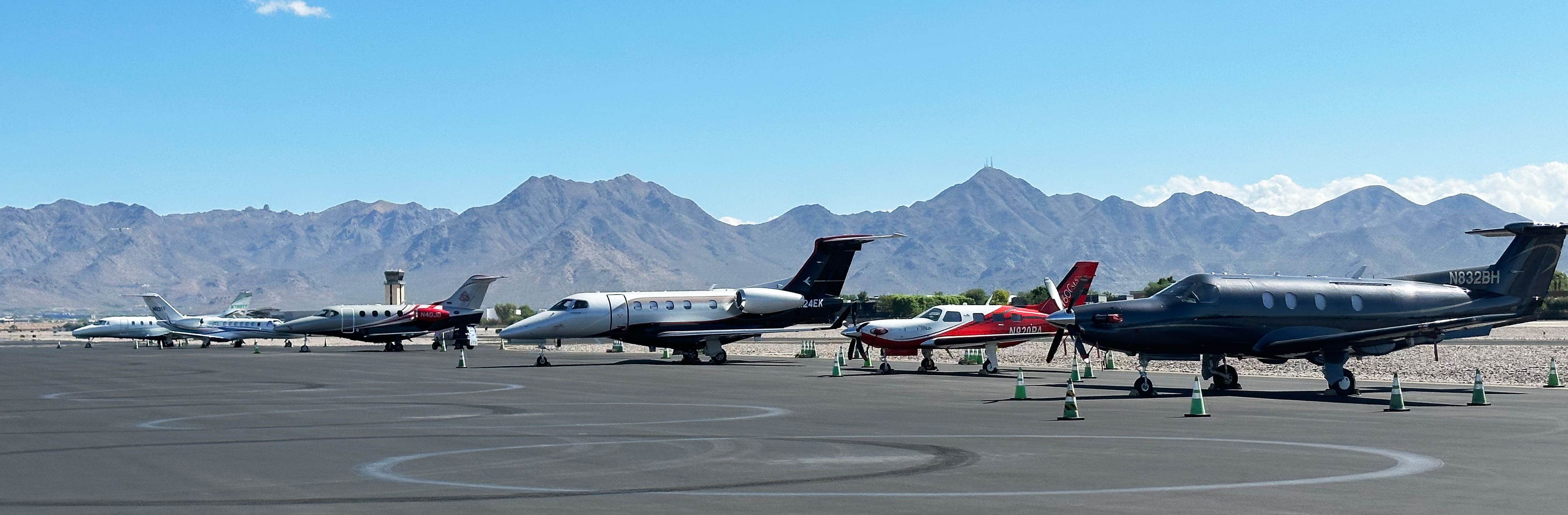 parked personal jets with mountains in the background